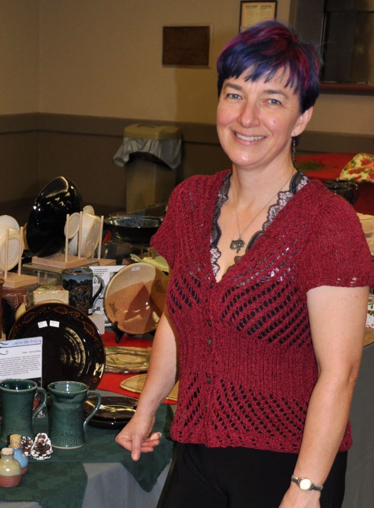 Karina Bates, standing in front of a display of some of her pottery